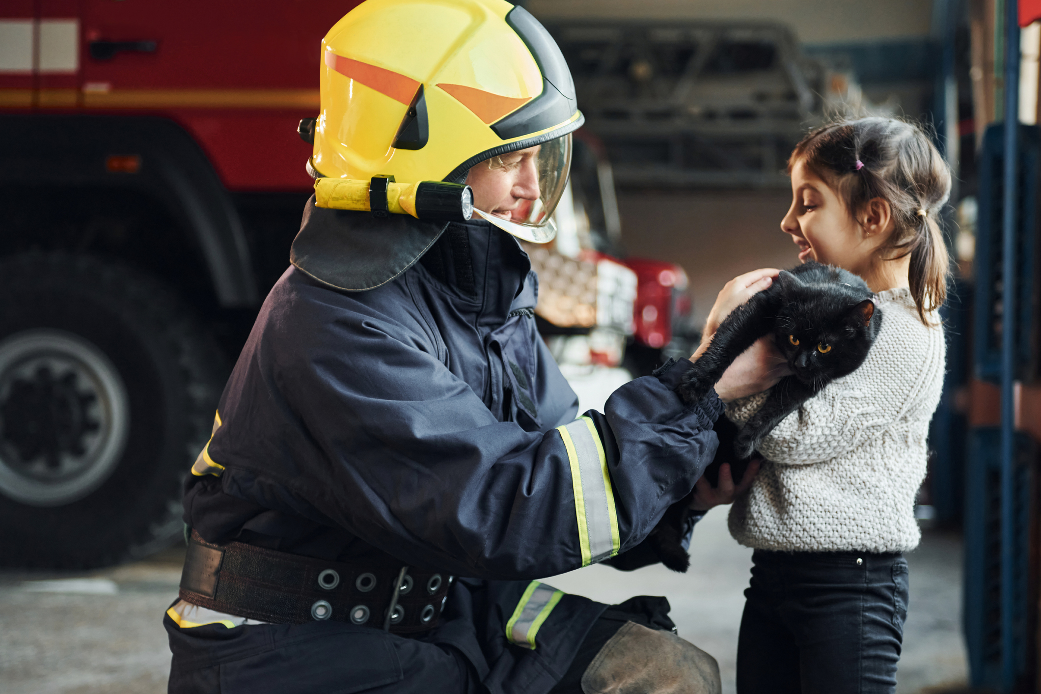 Firefighter and girl holding black cat for pet fire safety demonstration