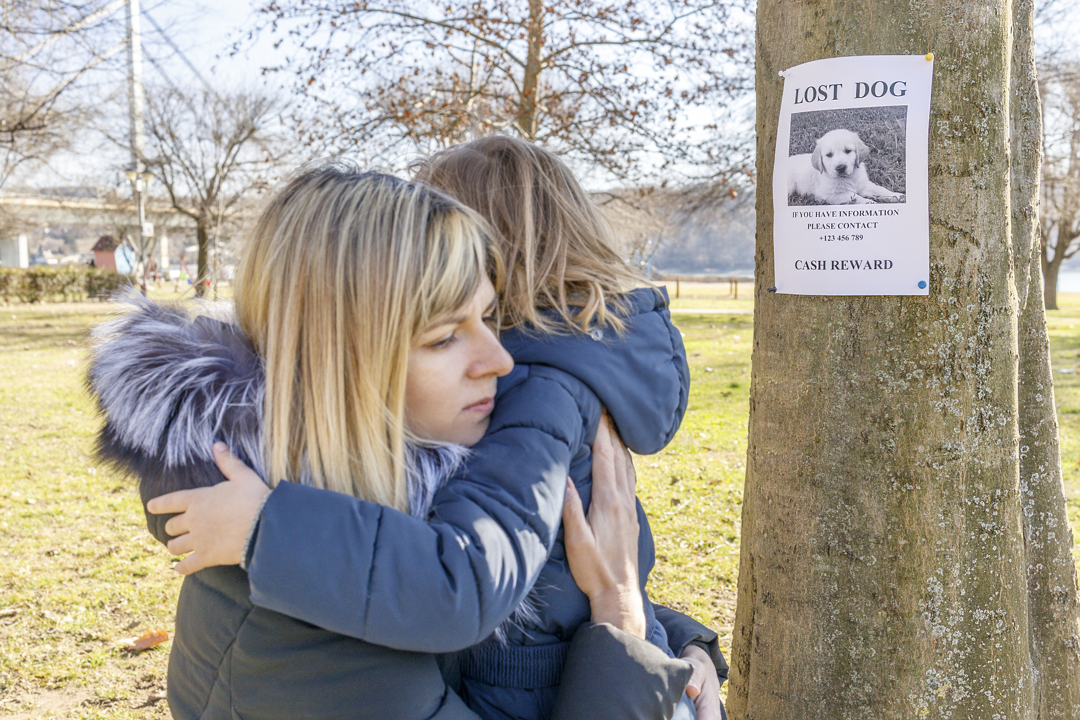 Mother and daughter hugging while putting up flyers for their lost pet