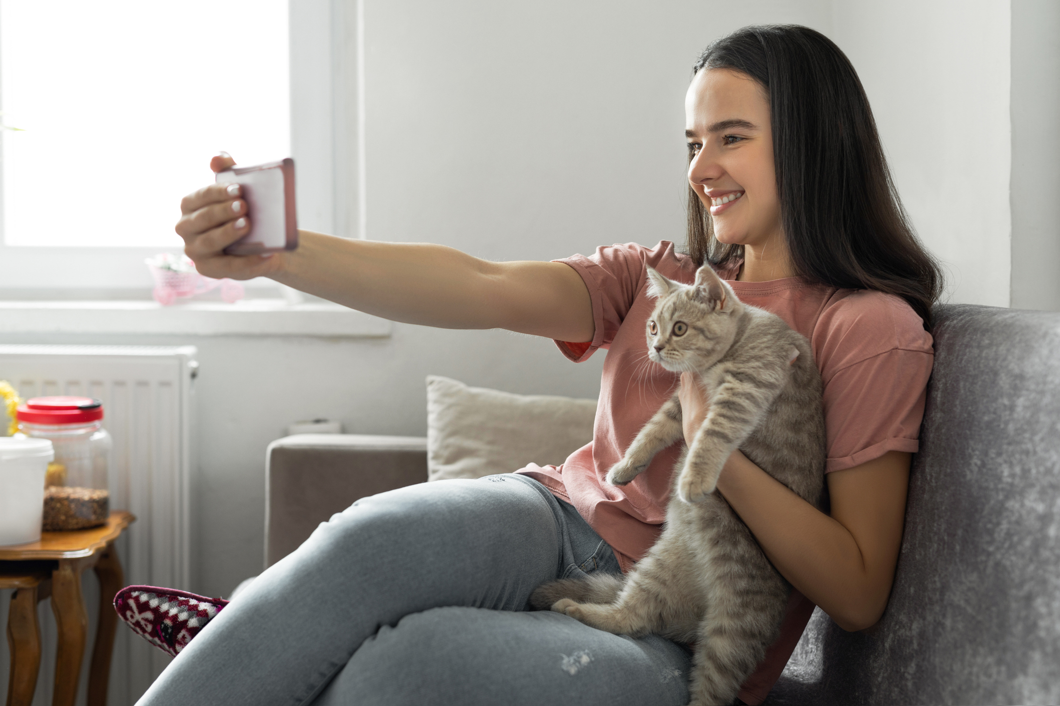 Woman taking a selfie with her gray tabby cat